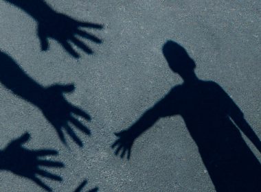 child's shadow on the ground reaching towards several outstretched hands