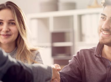 Young couple shake hands with a business person