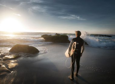 Man with surfboard looks at the ocean