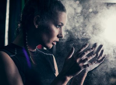 athletic woman applying chalk to her hands