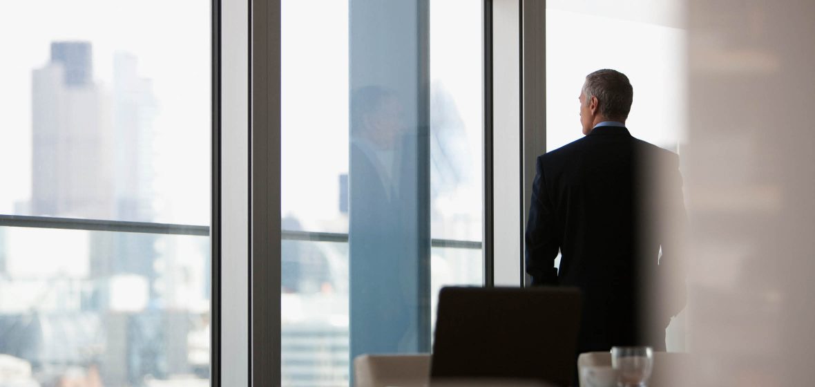 Corporate businessman in a boardroom looking out the window