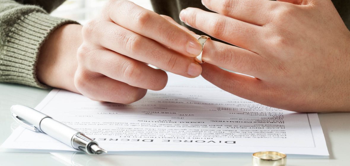 Man takes wedding ring off finger while reading divorce papers