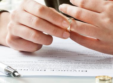 Man takes wedding ring off finger while reading divorce papers