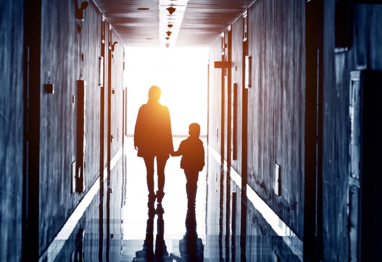 Silhouette of adult and child walking down a hallway