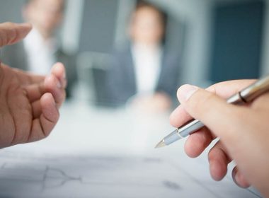 A person writes on a document while attending a meeting