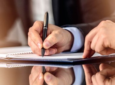 Man signs a document, witness by a second man