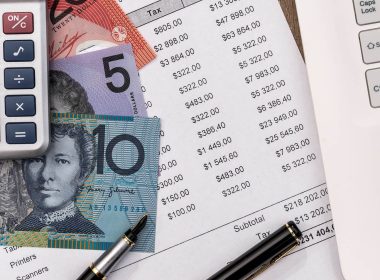 calculator, money and bank statement next to a laptop on a desk