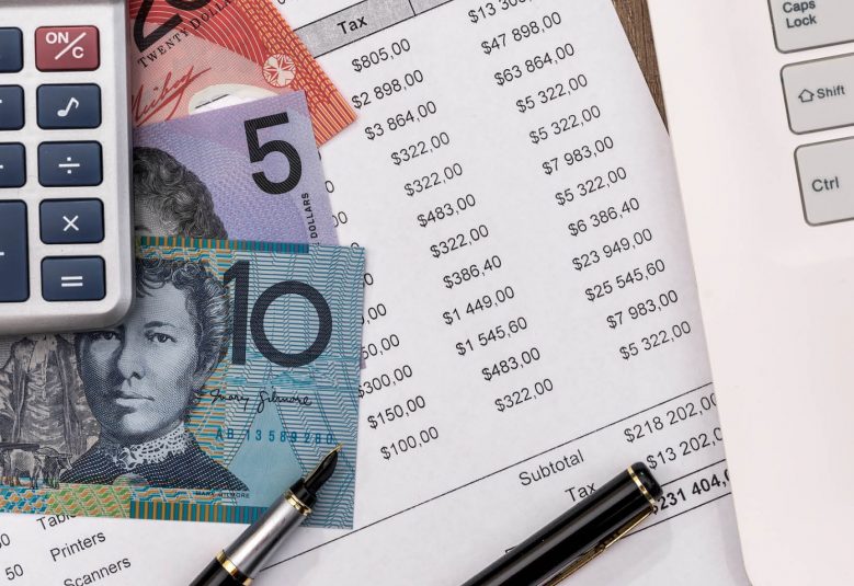 calculator, money and bank statement next to a laptop on a desk