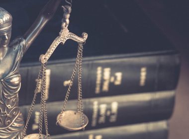 A stack of law books next to a status of Lady Justice