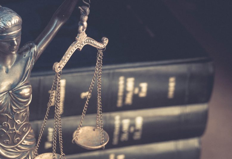 A stack of law books next to a status of Lady Justice