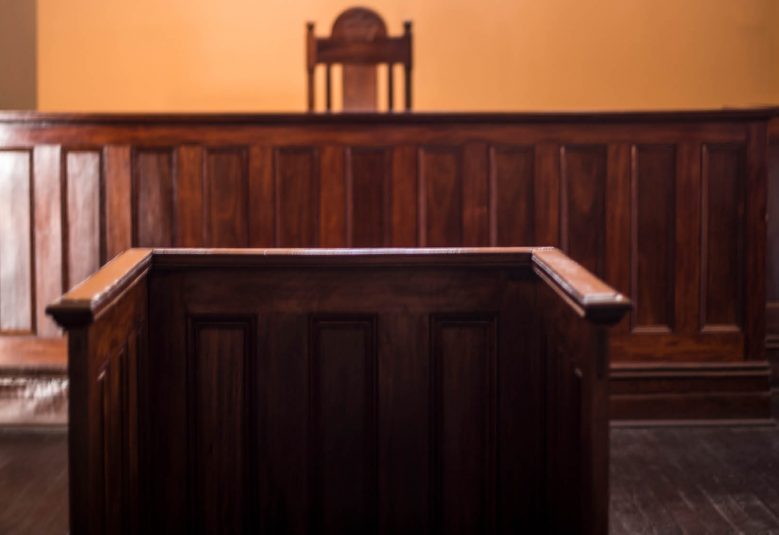 An empty witness box faces an empty court bench