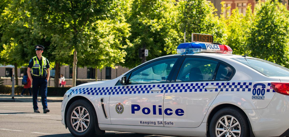 A police officer stands next to a police car