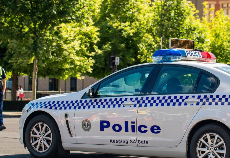 A police officer stands next to a police car