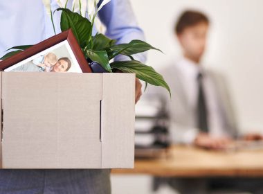 man carries box of personal items across an office