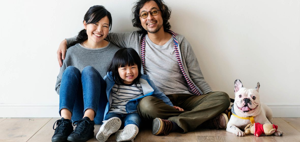 Man and woman sit on the floor with a child and a dog