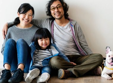 Man and woman sit on the floor with a child and a dog