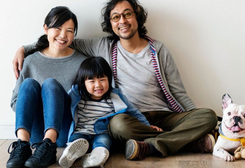 Man and woman sit on the floor with a child and a dog
