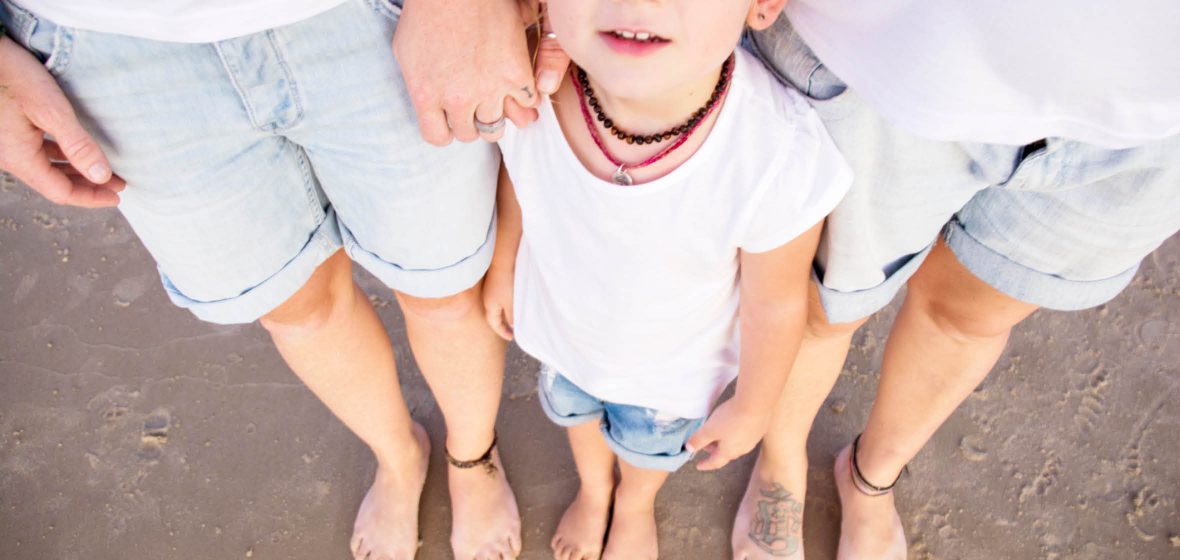 Two adults stand with a child on a beach.