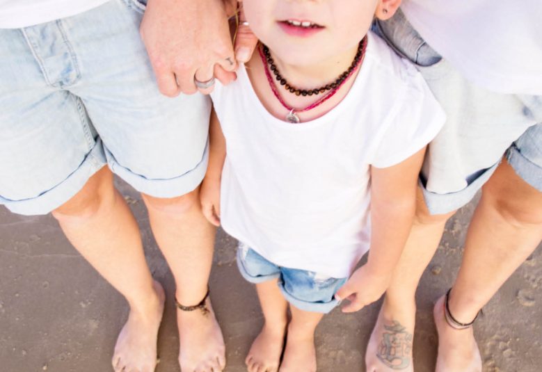 Two adults stand with a child on a beach.