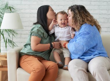 Two women sitting on the couch holding a child