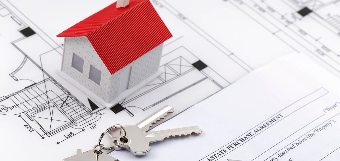 Scale model of house sits on housing plans next to a set of keys