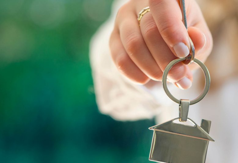 Woman's holding key chain in the shape of a house