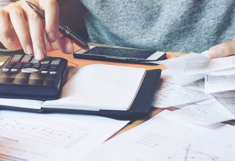 man uses calculator to add up receipts