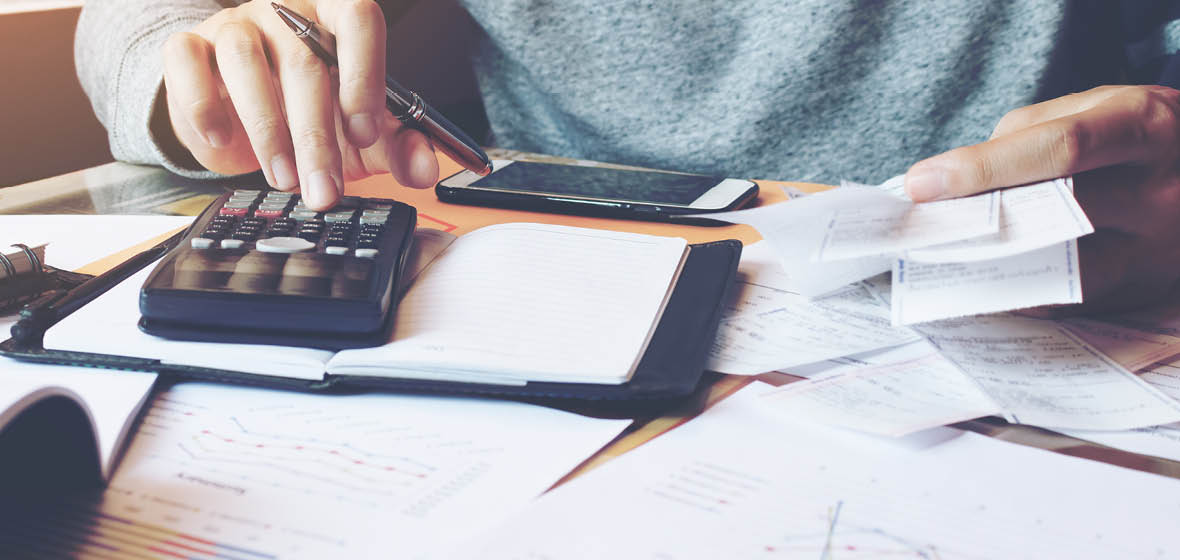 man uses calculator to add up receipts