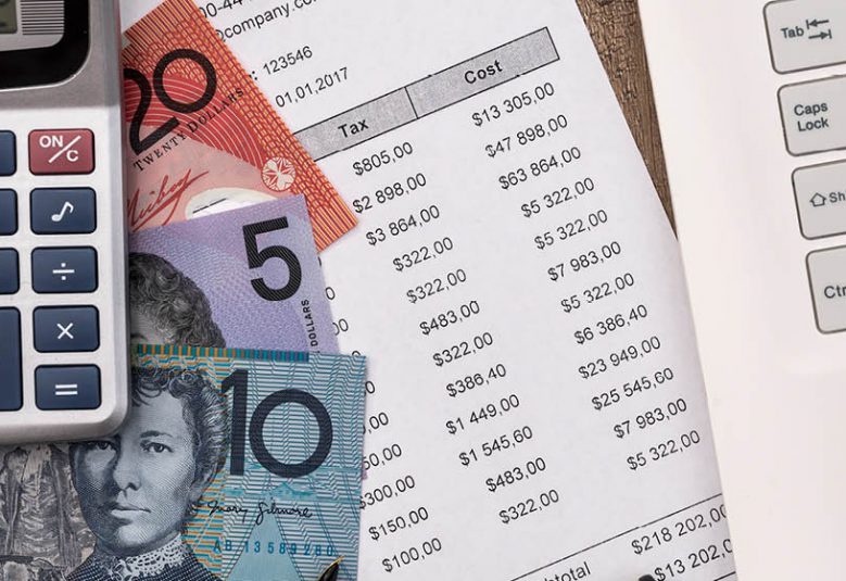 Calculator, Australian bank notes and a bank statement on a desk, next to a laptop