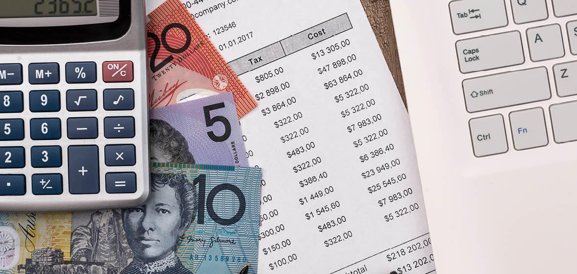 Calculator, Australian bank notes and a bank statement on a desk, next to a laptop