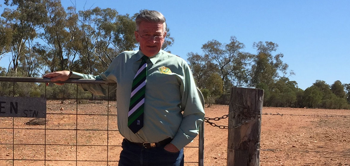 Cobar solicitor and conveyancer Peter Payne standing in front of a barbed wired fence in regional NSW.