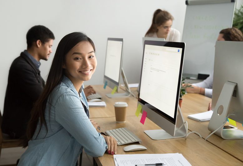 Young employee, sitting at her computer smiling