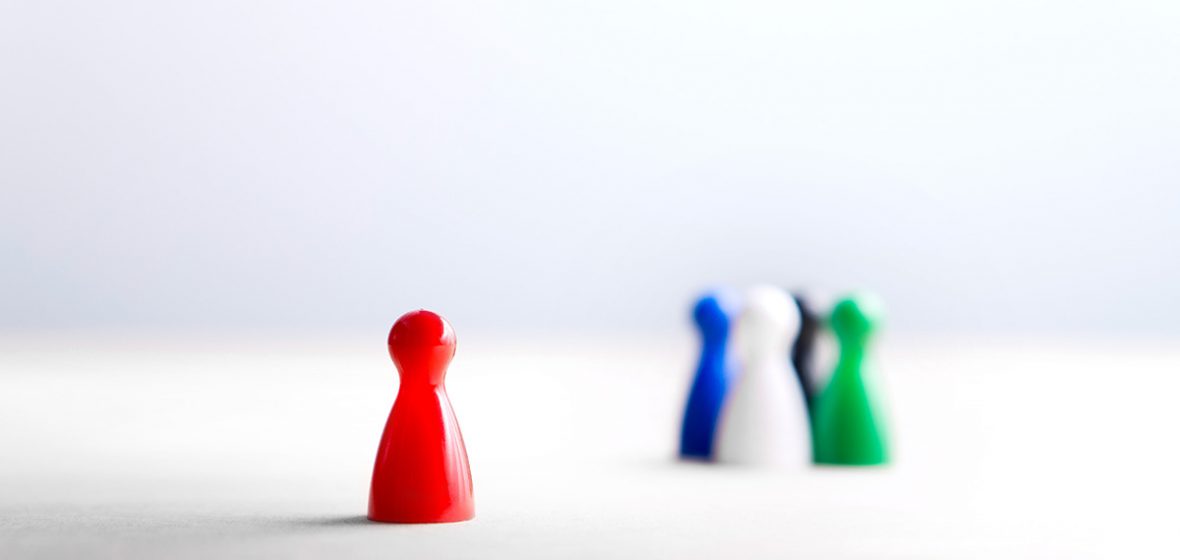 Board game pawns on wooden table. One pawn is positioned away from the others.