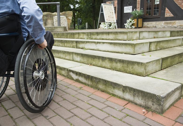 Wheelchair user in front of staircase barrier
