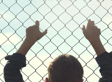 child holding onto wire fence