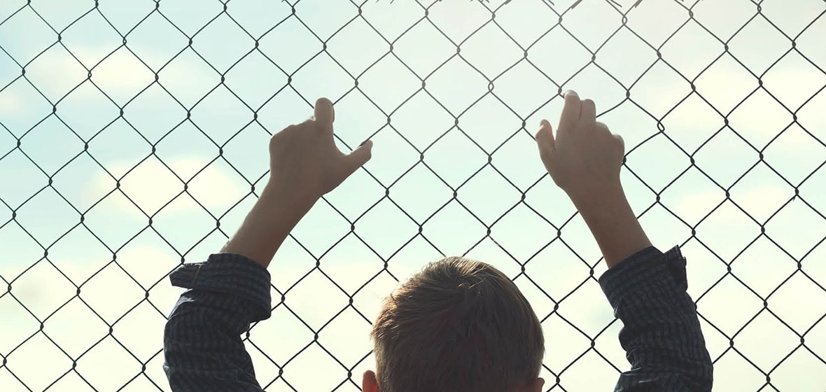 child holding onto wire fence