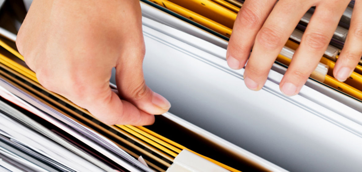 woman's hands going through filing cabinet