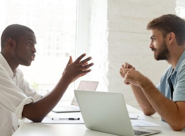 two men sitting at a desk talking