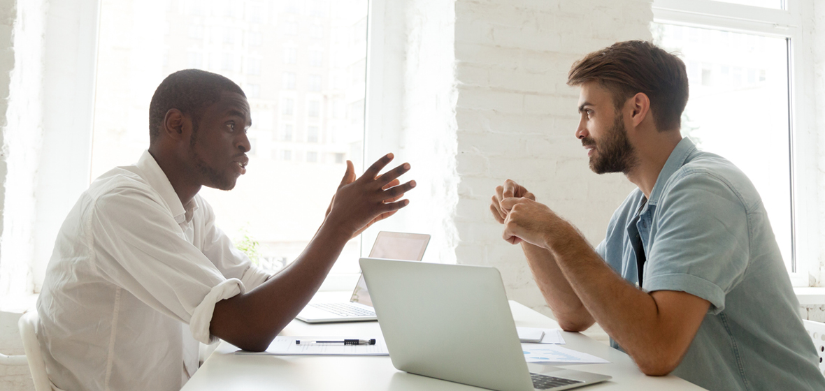 two men sitting at a desk talking