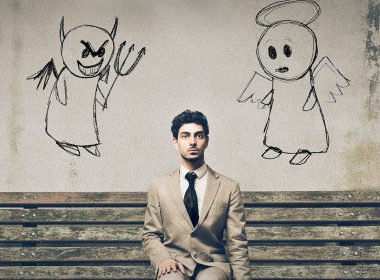 Man sitting on bench with an angel and a devil on his shoulders