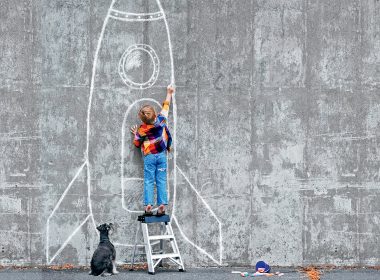 Boy drawing on wall while dog is watching