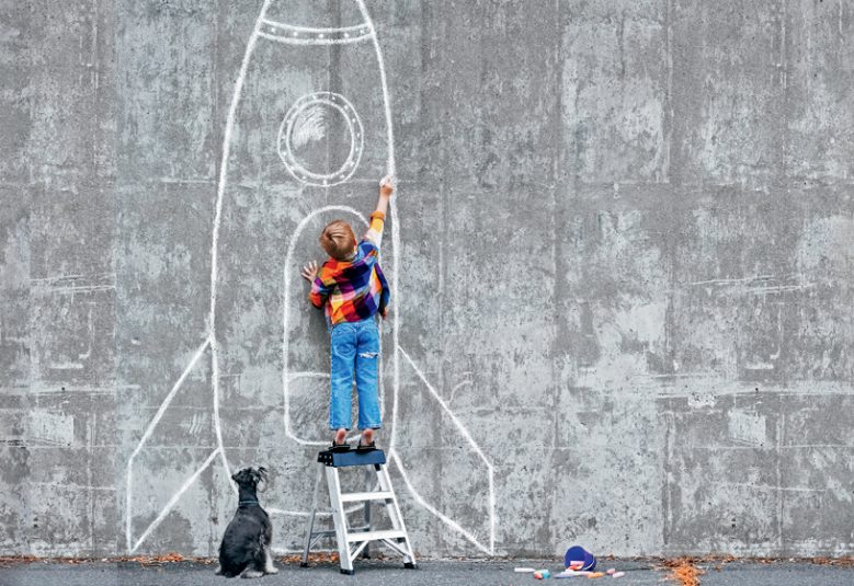 Boy drawing on wall while dog is watching