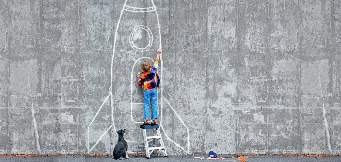 Boy drawing on wall while dog is watching