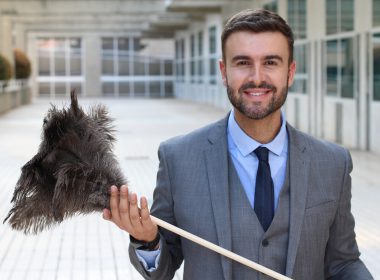 Businessman holding a feather duster.