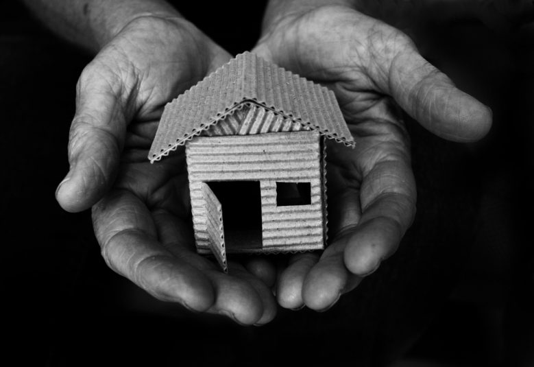 Hands holding small cardboard house