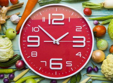 A clock surrounded by vegetables