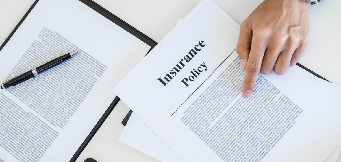 A man reviews insurance policy documents on a desk