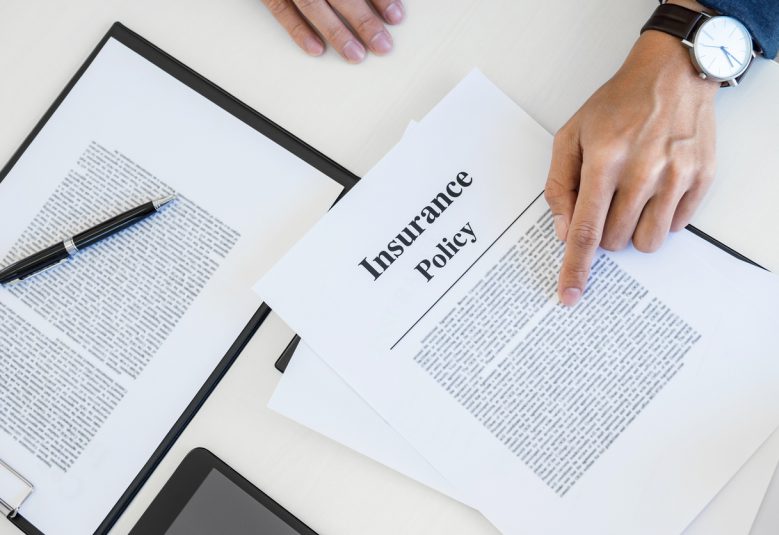 A man reviews insurance policy documents on a desk