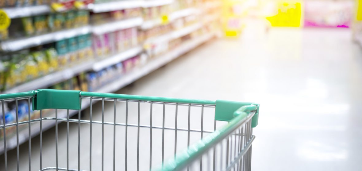 Shopping trolley being pushed down an aisle of a supermarket