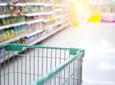 Shopping trolley being pushed down an aisle of a supermarket